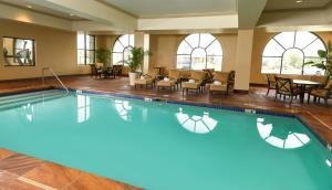 奥罗拉丹佛机场伍利经典套房酒店的大楼内一个带椅子和桌子的游泳池