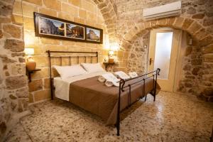 卡洛维诺DOMUS CESARE-dimora storica totalmente in pietra nel cuore del centro storico con cabina doccia pietra in camera e zona relax esterna-historic residence entirely made of stone in the heart of the historic center with stone shower cabin in the room的卧室配有一张石墙床