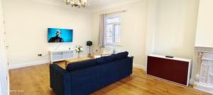 哈罗Marigold Villa的客厅配有蓝色的沙发和电视