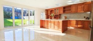 哈罗Marigold Villa的大型厨房设有木制橱柜和大窗户