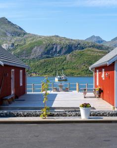拉姆贝格Lofoten Cabins - Kåkern的码头上有两个红色的建筑,水中有一船