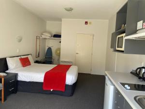 惠灵顿Ascot Motor Lodge的小房间,配有一张带红色毯子的床