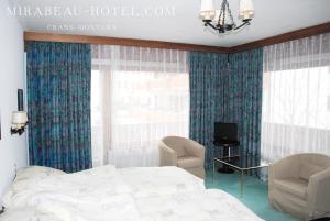 克莱恩 蒙塔纳米拉波酒店的一间卧室配有一张床、两把椅子和电视
