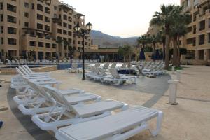 索瓦马Samarah Dead Sea Resort Studio-CP6 Traveler Award 2023 Winner的庭院里一排白色的躺椅
