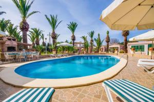 阿尔库迪亚Can Comaro的一座带桌椅和棕榈树的度假村游泳池
