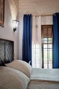 扎霍拉Hacienda Sajorami的一间卧室配有一张带蓝色窗帘的床和一扇窗户
