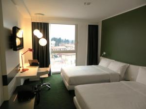 卡萨诺韦米兰马尔彭萨机场创意酒店的酒店客房设有两张床、一张书桌和一个窗户。