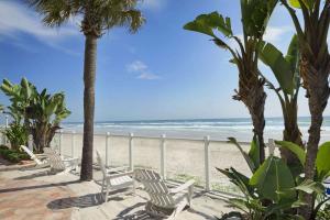 代托纳海滩热带海洋戴斯酒店的海滩上,有椅子和棕榈树,还有大海