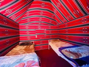 瓦迪拉姆Bedouin host camp& with tour的红色墙面客房,配有两张床