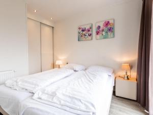 贝梅伦Holiday Home Green Resort Mooi Bemelen by Interhome的卧室内的一张白色床,墙上挂着两张照片