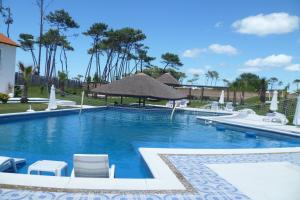 埃斯特角城Palmeras Beach Hotel的度假村的游泳池配有椅子和遮阳伞