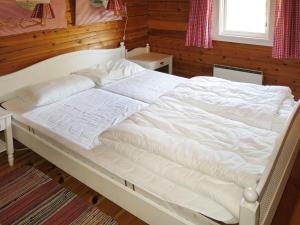 HolsenChalet Fjellro - FJS103 by Interhome的卧室设有一张白色大床,拥有木墙