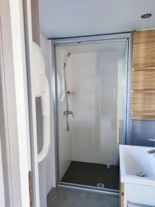 翁赞Assist' Mobil home 330 - Mobil Home original 3 chambres 6 personnes的浴室里设有玻璃门淋浴