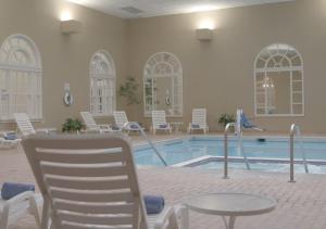 格伦斯福尔斯昆斯伯里酒店的一个带白色椅子和桌子的游泳池以及一个游泳池