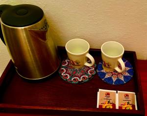 普里什蒂纳Convini Bed & Bathroom Homestay的咖啡壶旁木桌上的两杯