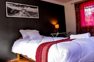 乌鲁班巴The Willow B&B的一间卧室设有两张带白色床单和红色窗户的床。