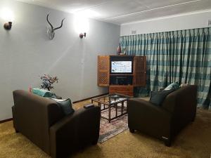 爱德华港Apt 66 Eden Wilds Umtamvuna Getaway的客厅配有两把椅子和电视