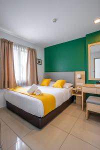 吉隆坡V Hotel Pudu Kuala Lumpur的一间卧室设有一张大床和绿色的墙壁
