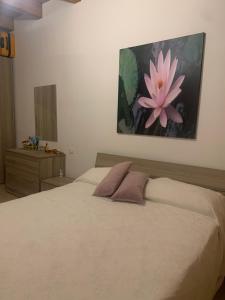 索威拉托玛里纳Casa Dodò al mare di Soverato的卧室配有一张大床,墙上挂着粉红色的花朵