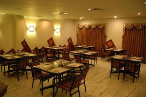 坦贾武尔那南酒店的用餐室配有桌椅和窗帘