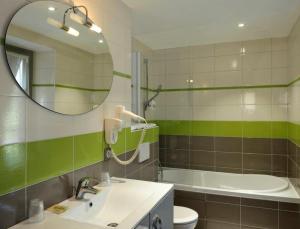 朗热Logis Hôtel Auberge de la Bonde的浴室配有盥洗盆、镜子和浴缸