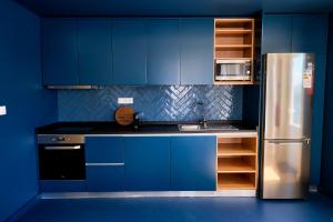 英雄港Mid-Atlantic Boutique Hostel的厨房配有蓝色橱柜和不锈钢冰箱