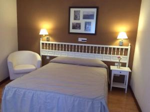 萨塞东玛丽布兰卡乡村酒店的一间卧室配有一张床、一把椅子和两盏灯。