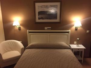 萨塞东玛丽布兰卡乡村酒店的一间卧室配有一张床、一把椅子和两个灯