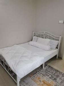 克提Homestay Qaseh Kerteh的一张带金属框架和白色床单的床