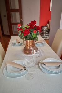 毕尔巴鄂Apartamento BIO Exclusivo con mirador en Bilbao y aparcamiento público gratuito的一张桌子,上面有盘子和玻璃杯,花瓶上装有红色的花