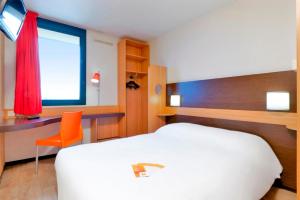 热讷维耶普瑞米尔巴黎西杰内维利尔经典酒店的一间卧室配有一张床、一张书桌和一个窗户。