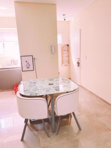布宜诺斯艾利斯LUMIÈRE ALICAR APPTS &SUITES的一间带桌子和两把白色椅子的用餐室