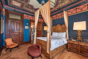 旧金山Chateau Tivoli Bed and Breakfast的一间卧室配有一张天蓬床和一把椅子