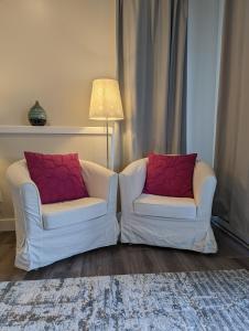 邓肯Maple Rise Guesthouse的客厅配有两把带红色枕头的白色椅子