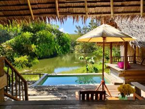 宋卡塔省帕拉度假村的一个带遮阳伞和桌椅的游泳池