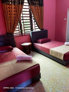 Kampung RajaTeratak Ammara Homestay Besut with private pool的配有粉红色墙壁和窗户的客房内的两张床