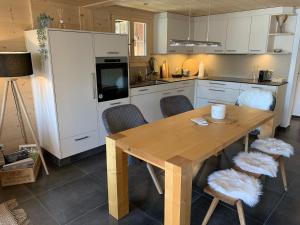 伦克Büehl Lenk的厨房配有木桌和白色橱柜。