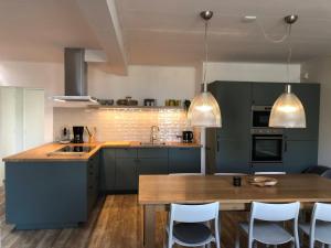 比伦Naar Zee op Ameland的厨房配有绿色橱柜和木桌
