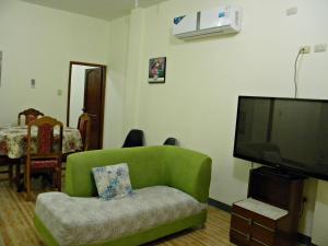 洛佩斯港Casa Blanca Puerto López的客厅配有绿色沙发和平面电视