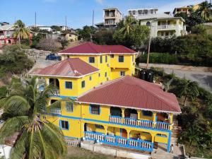 CanouanBay View Apartment 4 - Canouan Island的黄色的房屋,有红色的屋顶