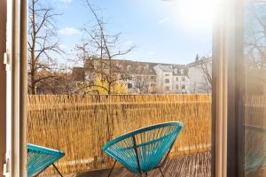 慕尼黑Flatista Homes - Hirschgarten的阳台设有两把蓝色椅子和围栏