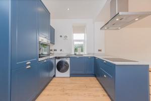 Bannockburn4 Bed cottage with Hot tub的厨房配有蓝色橱柜和洗衣机。