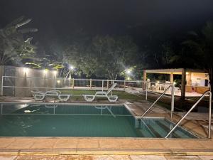 巴雷里尼亚斯CASA DUPLEX em CONDOMÍNIO à beira do RIO PREGUIÇAS的游泳池晚上有两把椅子
