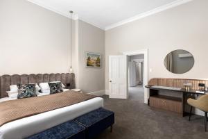 芒特甘比尔干比尔山宾馆的一间卧室配有一张床、一张书桌和一面镜子