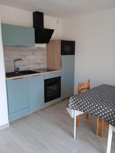普洛埃默Appartement PLOEMEUR-Fort Bloqué的厨房配有蓝色橱柜、桌子和水槽