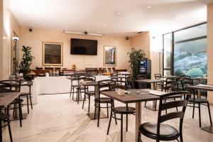 特伦托布里科斯里昂酒店的餐厅设有桌椅和平面电视。