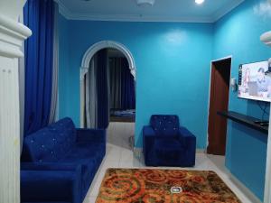 加央Homestay Dalia, Beseri, Perlis的客厅设有蓝色的墙壁和蓝色的椅子