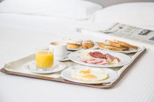 布林迪西行政精品酒店的包括早餐食品和一杯橙汁的托盘