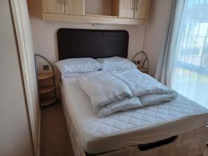 斯凯格内斯6 Berth Caravan Happy Days North Chapel St Leonards的一间卧室配有一张带白色床单的床和一扇窗户。