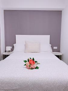 阿尔卡拉德瓜代拉Hostal El Castillo Alcala De Guadaira的一张白色的床,上面有一束鲜花